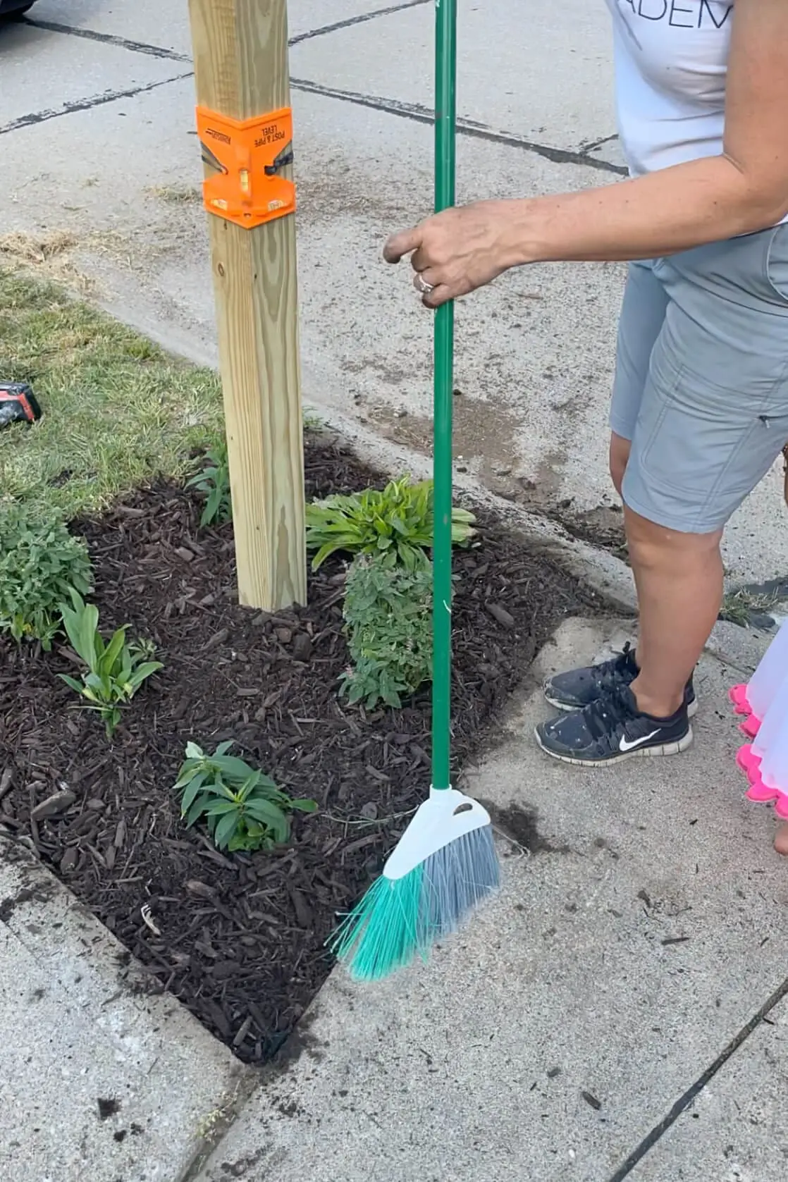 Cleaning up sidewalk after planting a flower bed.